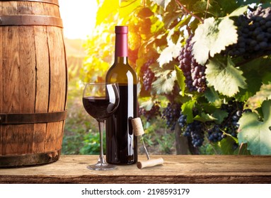 Pouring red wine into the glass against wooden background.