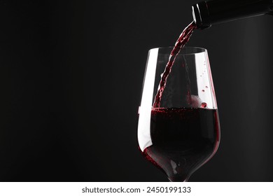 Pouring red wine into glass against black background, closeup. Space for text - Powered by Shutterstock