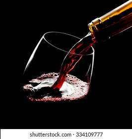 Pouring red wine into the glass against black background
