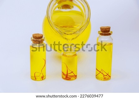 Pouring saffron tincture into glass jars on a white background.
