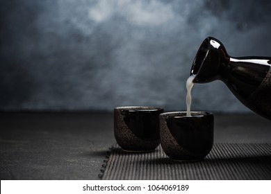 Pouring sake into sipping ceramic bowl.