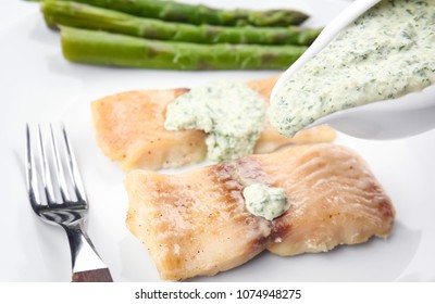 Pouring sauce on delicious fish fillet, close up