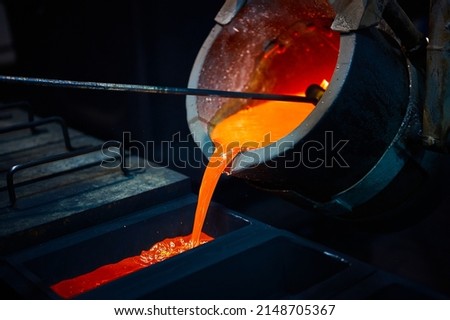 Pouring silver into graphite casting form in dark workshop