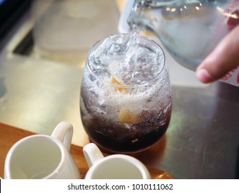 Pouring Soda Over Glass Of Ice Black Tea With Ginger Ale. Lifestyle Concept.