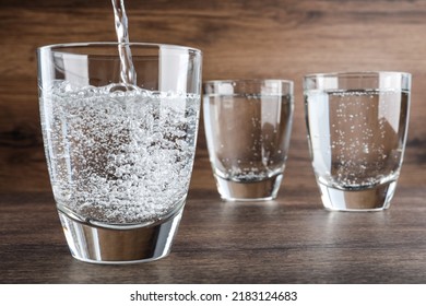 Pouring Soda Water Into Glass On Wooden Table