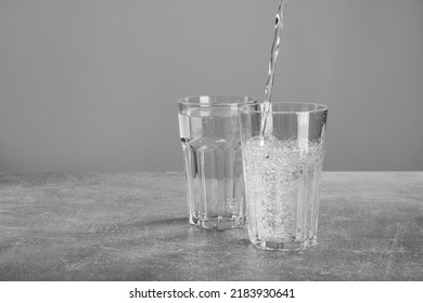 Pouring Soda Water Into Glass On Grey Table. Space For Text