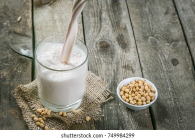 Pouring Soy Milk On Rustic Wood Background, Copy Space