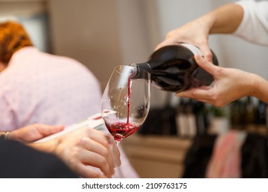 Pouring spanish red wine into a wine during a party,close-up.