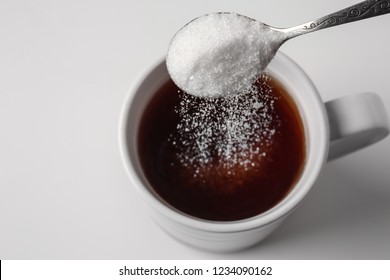 Pouring Of Sugar Into Cup Of Coffee On Light Background