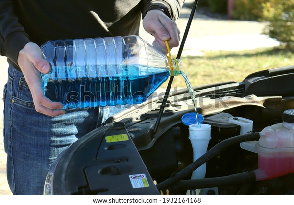 Pouring summer liquid or blue car\
liquid to wash the car screen. The concept of car\
service.