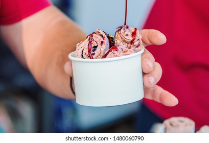 Pouring Syrup On Ice Cream Rolls In Paper Bowl.