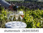 Pouring and tasting of white and rose sparkling wine brut, grand reserve, champagne in Ay-Champagne on green hilly vineyards and view on old wine making village in Vallee de la Marne, Champagne France