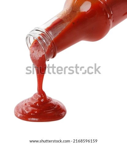 Pouring tasty ketchup from glass bottle on white background, closeup