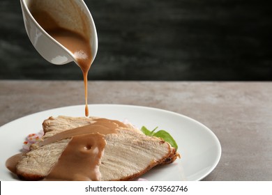 Pouring Tasty Turkey Gravy Onto Sliced Meat On Plate Against Dark Background