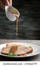 Pouring Tasty Turkey Gravy Onto Sliced Meat On Plate Against Dark Background