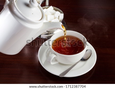 Pouring tea into a white tea cup