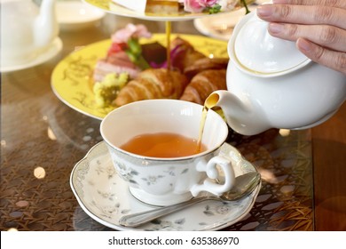 Pouring tea from vintage teapot to the cup, English Tea Time. - Shutterstock ID 635386970