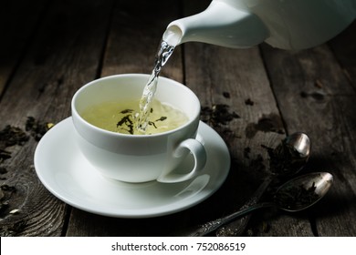 Pouring Tea In White Cup, Rustic Wood Background