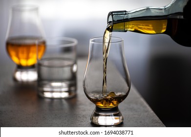 Pouring In Tulip-shaped Tasting Glass Scotch Single Malt Or Blended Whisky And Glas Of Water