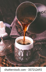 Pouring turkish coffee into traditional embossed metal cup.Toned