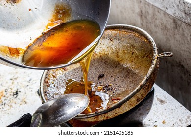 Pouring Used Cooking Oil From Frying Pan Into Colander.