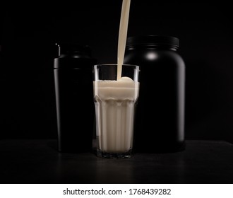 Pouring Vanilla Protein Shake To Glass With Black Jars In Background