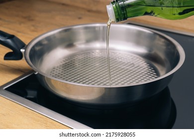 Pouring Vegetable Oil From Green Glass Bottle In Frying Pan.