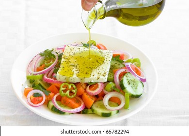 Pouring Virgin Olive Oil On Greek Salad