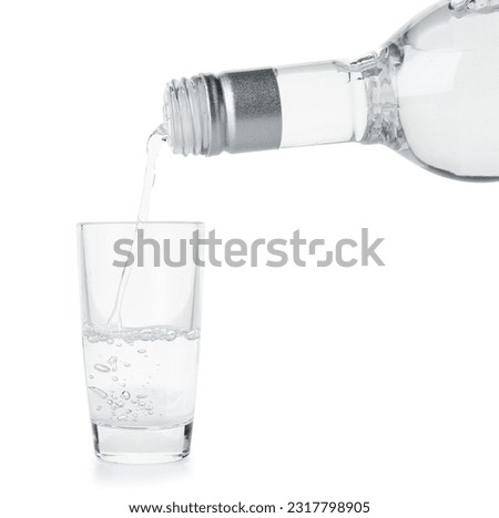 Pouring of vodka from bottle into glass on white background