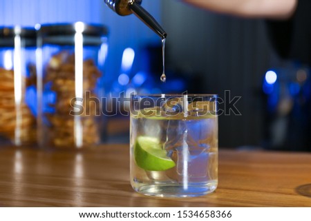 Pouring vodka into glass on wooden counter in bar