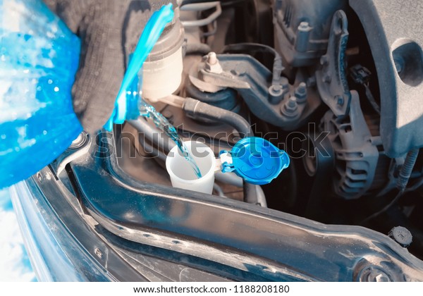 Pouring washer fluid into the\
car