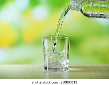 Pouring Water From Bottle On  Glass On Bright Background