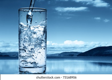 Pouring water into a glass against the nature background