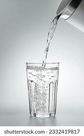 Pouring water into a glass on grey background, close-up