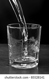 Pouring Water On A Glass On Black Background