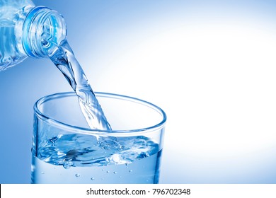 pouring water from plastic bottle into glass against blue gradient