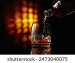 Pouring whiskey into a glass on a black background. Copy space.