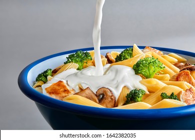 Pouring White Cream Sauce Over Plate Of Pasta.