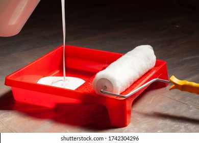 Pouring White Latex Paint In A Tray Before Painting A Room.