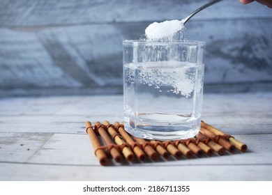 pouring white sugar in a glass of water on table 