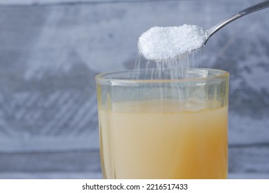 Pouring White Sugar In A Glass Of Water On Table 