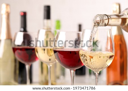 Pouring white wine from bottle into glass, closeup