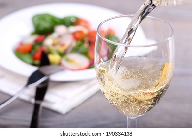 Pouring White Wine Into Glass And Food Background