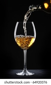 Pouring White Wine Into A Glass Over Black Background