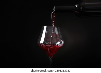 Pouring Wine From Bottle Into Glass On Black Background