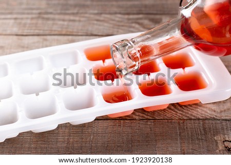Pouring wine in ice cube tray on a wooden table