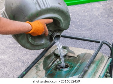 Pours gasoline from a barrel. A worker fills the generator with fuel. - Powered by Shutterstock