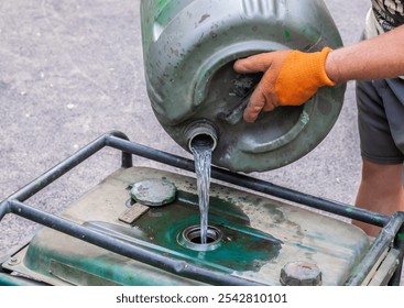 Pours gasoline from a barrel. A worker fills the generator with fuel. - Powered by Shutterstock