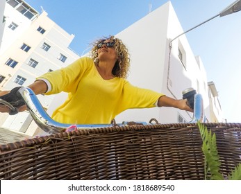 Pov Of Cheerful Happy Adult Young Caucasian Woman With Long Blonde Curly Hair Ride The Bike In Outdoor Leisure Activity - Coloured Portrait Of People In Activity - White Houses And Buildings Town 