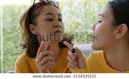 POV close-up face skin of mature elder mom and girl look at camera play fun game get dressed in asia mother day good life warm time. Cute teen people love enjoy social media app relax on sofa at home.